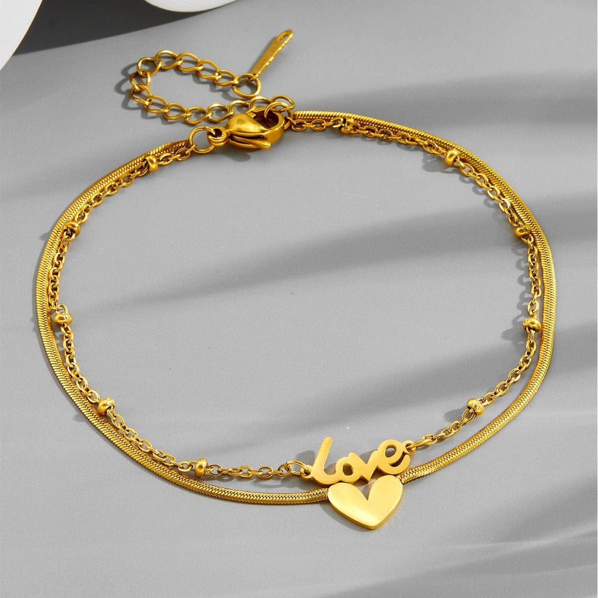Tobillera de acero de titanio con letra inglesa de oro de 18k