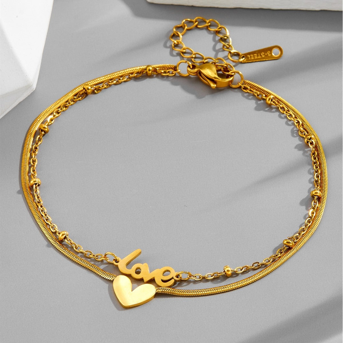 Tobillera de acero de titanio con letra inglesa de oro de 18k